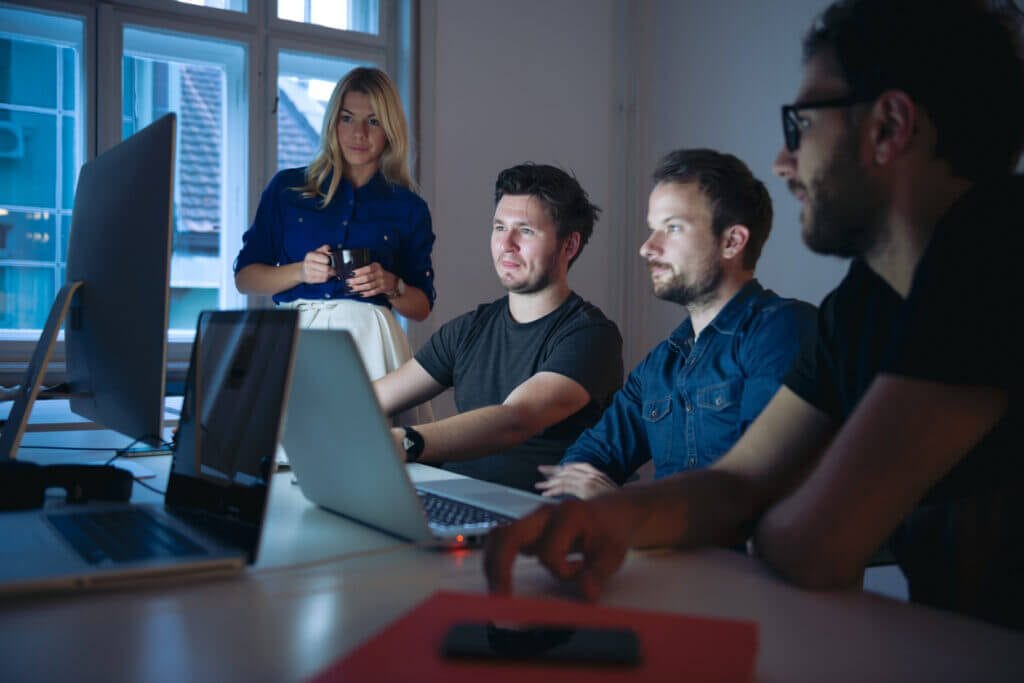 Employees gathered around a computer reviewing IT managed services and cybersecurity.