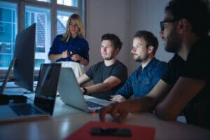 Employees gathered around a computer reviewing IT managed services and cybersecurity.