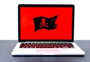 Laptop with malware and cybersecurity loaded with red background.