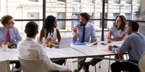 Group of employees working together in a glass conference room.