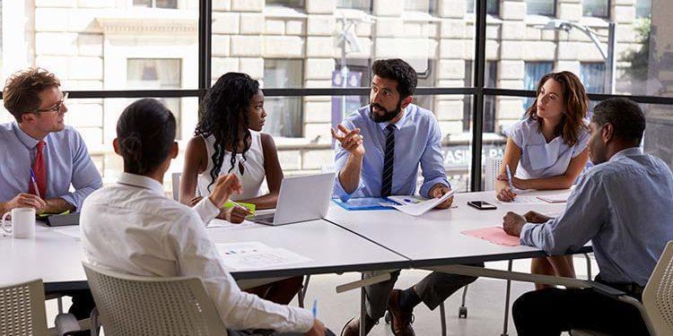 Group of employees working together in a glass conference room.