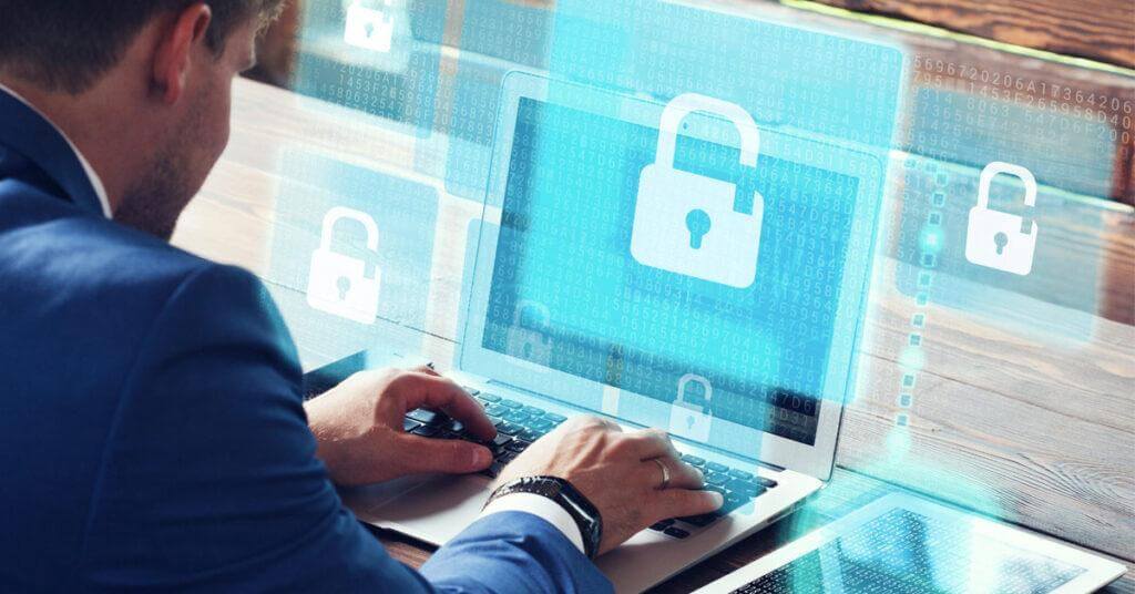 IT staff working at a laptop with a picture of a cyber lock on the screen.