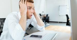 A businessman upset at a cybersecurity breach on his laptop.