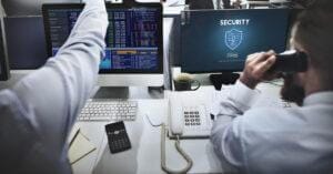 Cybersecurity staff sitting at desk reviewing security protocols.