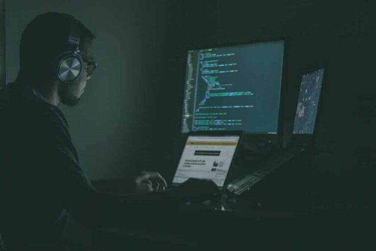 Employee working on IT projects from laptop with an extra monitor.