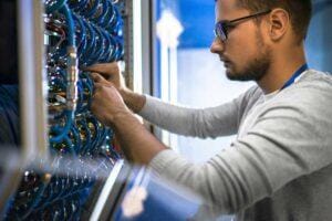 IT employee performing wiring maintenance in an IT closet.