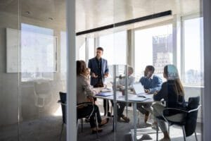 Employees meeting in a glass conference room about IT services and cybersecurity.