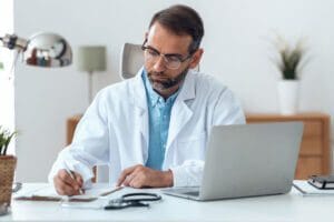 Male doctor working at desk computer.