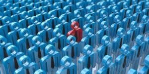 Human figures standing together with one stand out red one in the middle.