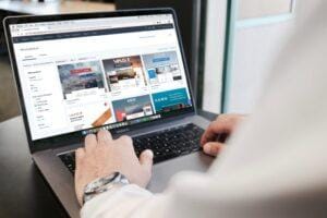Employee working on laptop with marketing designs loaded on screen.