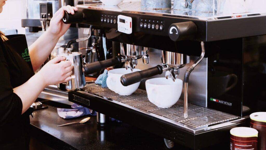 Barista steaming milk at an espresso machine.