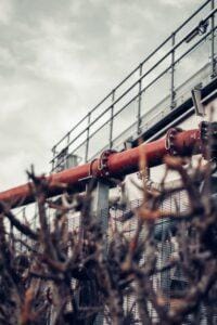 Industrial pipe outside a building with old grass up front.