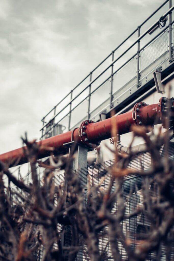 Industrial pipe outside a building with old grass up front.