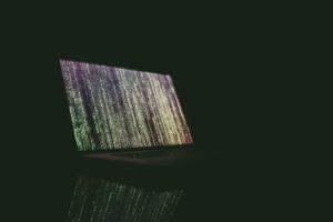 Laptop with code sitting in a dark office.