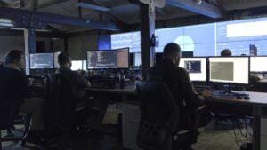 IT employees working at desktop computers in a SOC room.