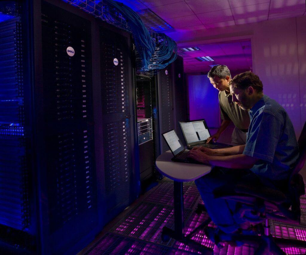 Science in HD- two men working on computers in front of a server