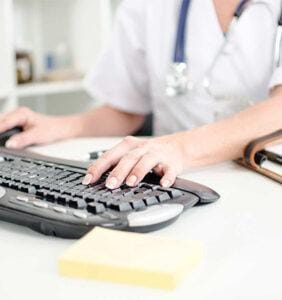 Healthcare worker using a computer keyboard in an office setting.
