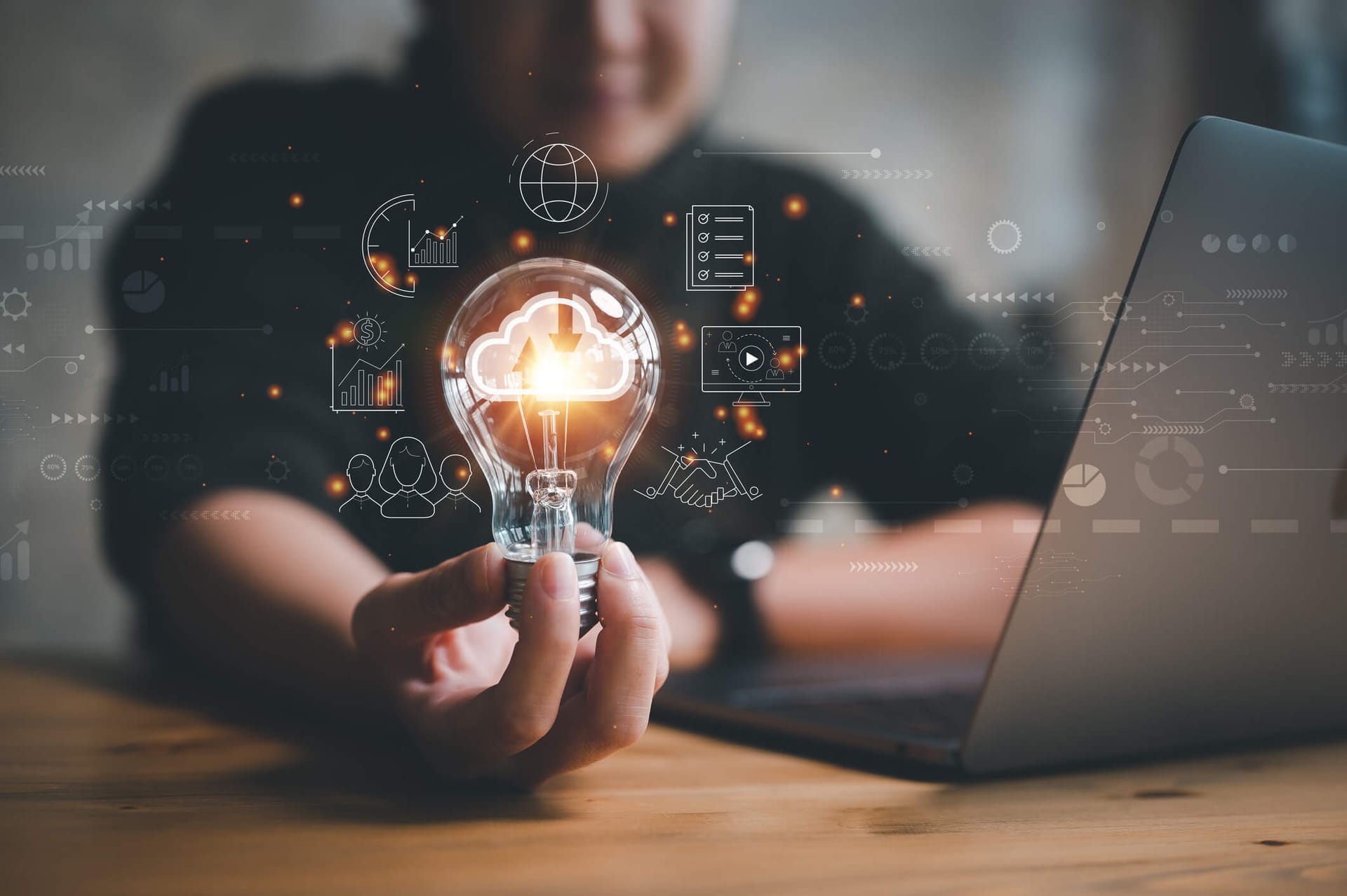Employee working at a laptop holding a lightbulb with cybersecurity graphics surrounding the image.